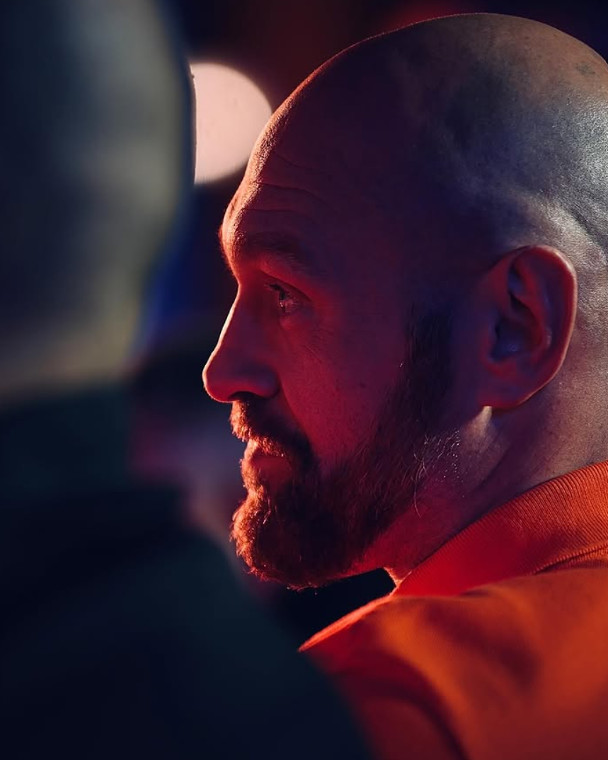 Close side profile of a boxer lit by red ringside light before a fight
