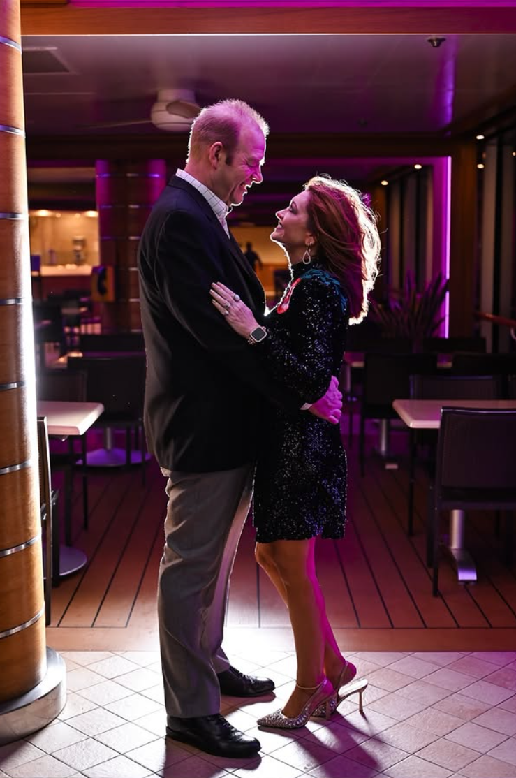 Couple dancing together under pink and purple lighting at an evening event