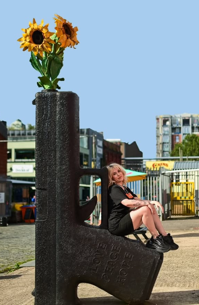 Portrait of a woman sitting on a sculpted bench in a city square on a bright summer day