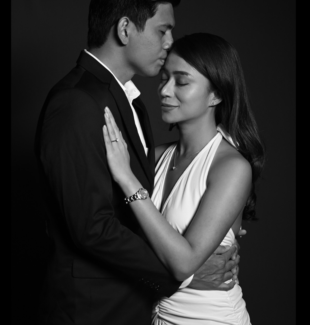 Black and white studio portrait of a couple in formal wear embracing
