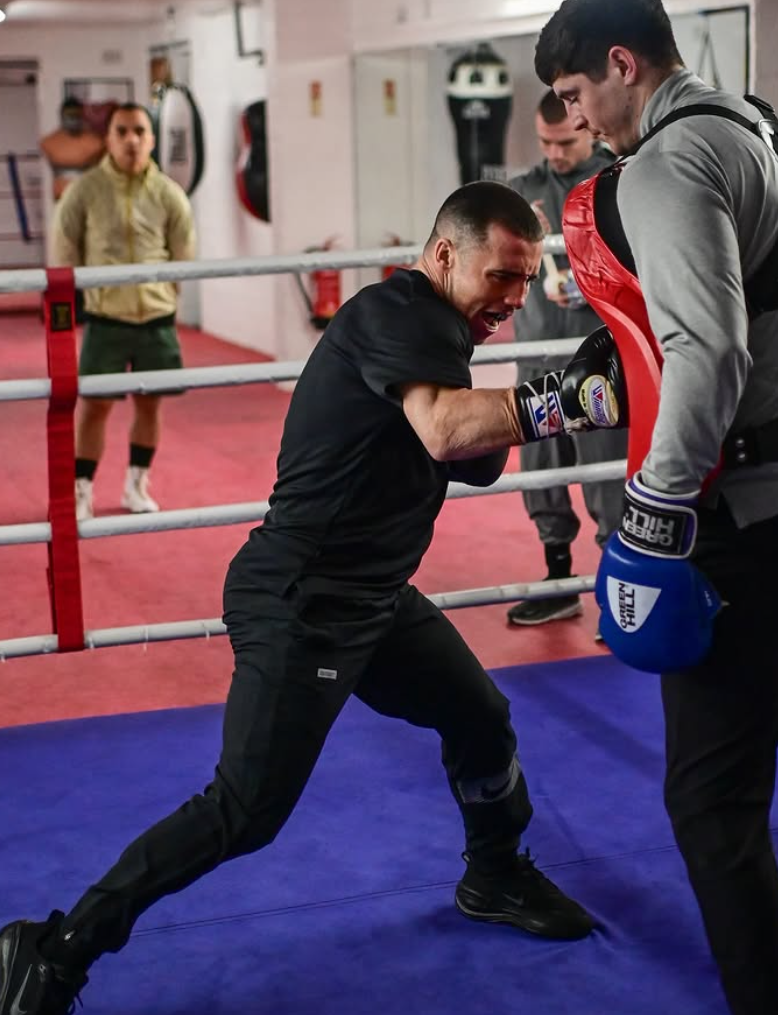 Boxer throwing a right hand into the pads during a training session in the ring